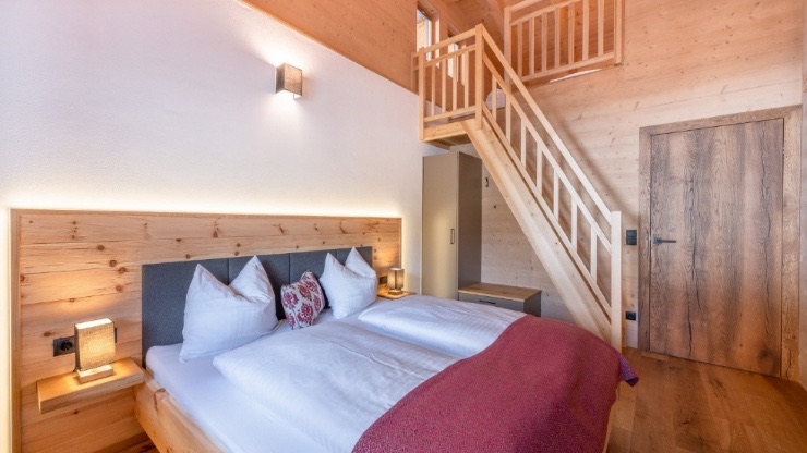Schlafzimmer mit Zirbenbett und Holzstiege zur Galerie