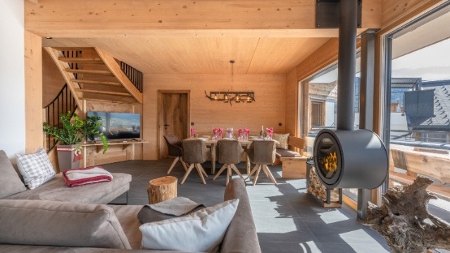 Wohnraum der Holz Lodge mit Holzstiege und Kaminofen